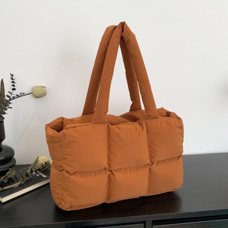 Soft Puffer Tote Bag in rust orange quilted puffer style on dark wood surface