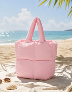 Mini Puffer Tote Bag in pink on sandy beach with sunglasses and seashells, ocean background