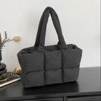 Soft Puffer Tote Bag in black with thick padded compartments on dark wood surface