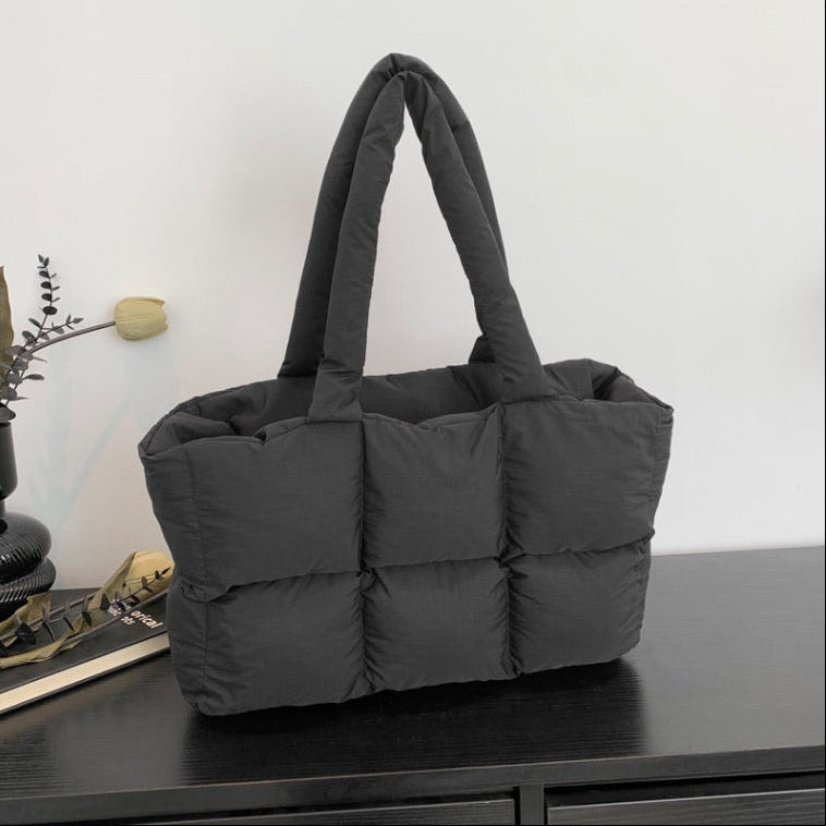 Soft Puffer Tote Bag in black with thick padded compartments on dark wood surface