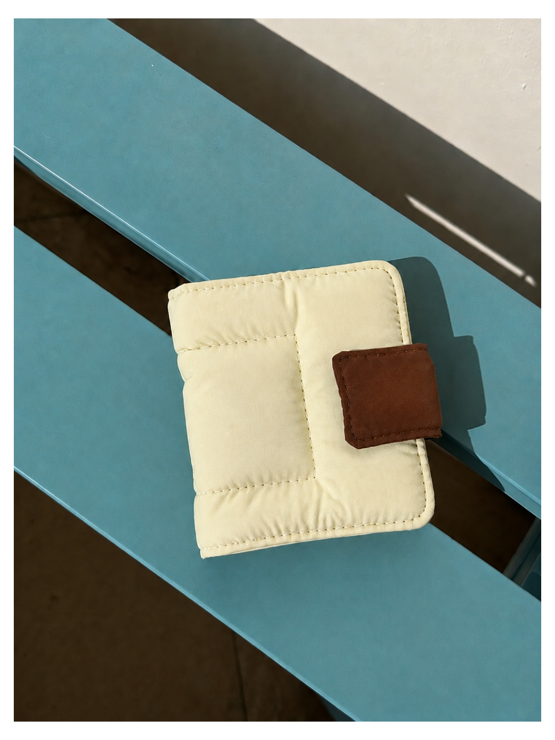 Toast Polaroid Memory Album - cream quilted mini photo album with brown leather tab closure on blue wood surface