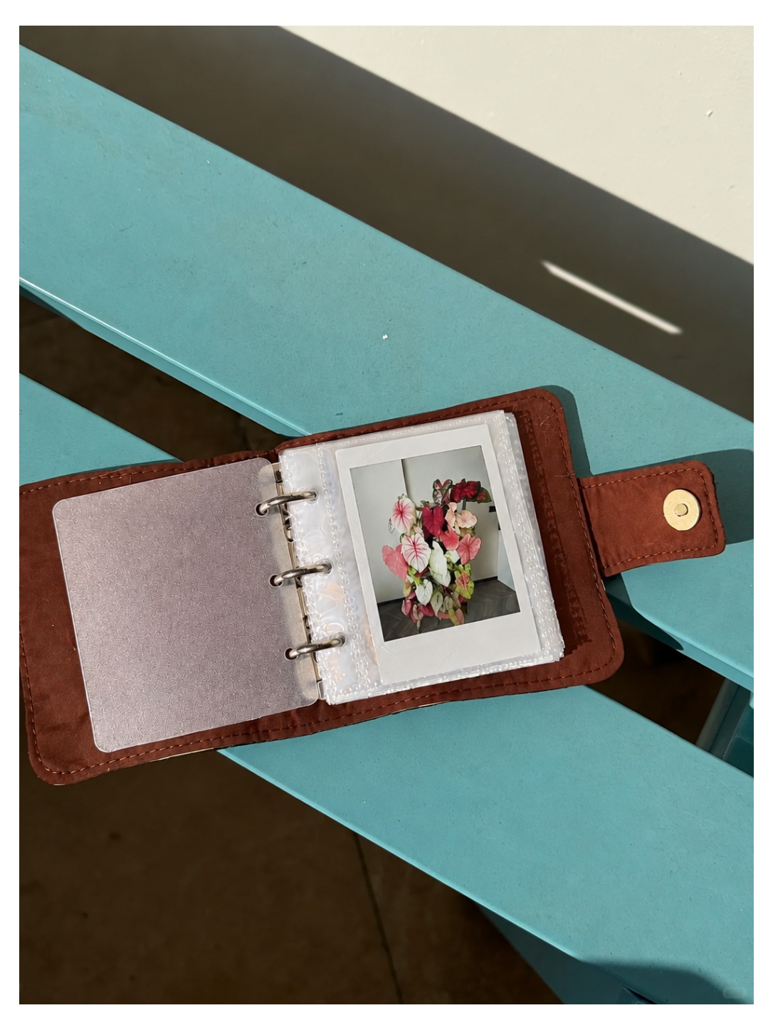Toast Polaroid Memory Album shown open on a turquoise surface with a sample instant photo inside