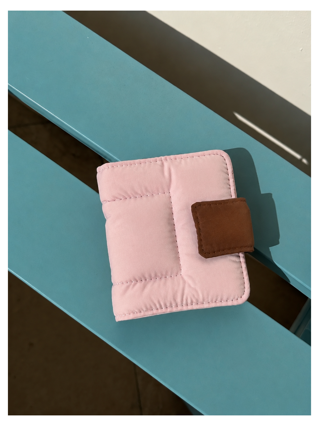 Toast Polaroid Memory Album - light pink quilted mini photo album with brown leather closure on blue wood surface