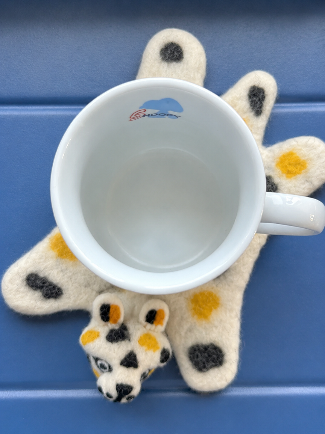 Wool Felt Animal Coaster - leopard-shaped felt coaster in cream and gold with charm, holding a coffee mug