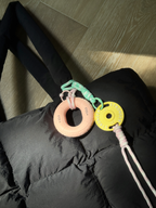 Mini Plate Bag Charm - weight plate charms in pink and yellow clipped to a black puffer bag strap